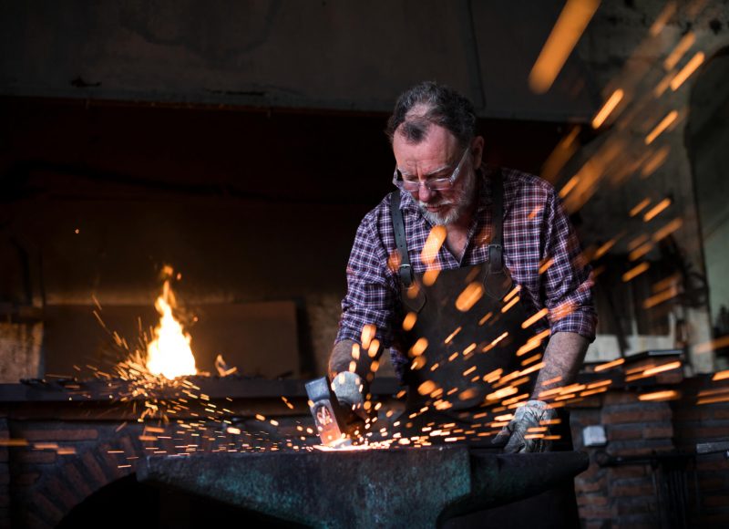 blacksmith-working-with-hammer-at-anvil-in-his-wor-F87ZZFG.jpg